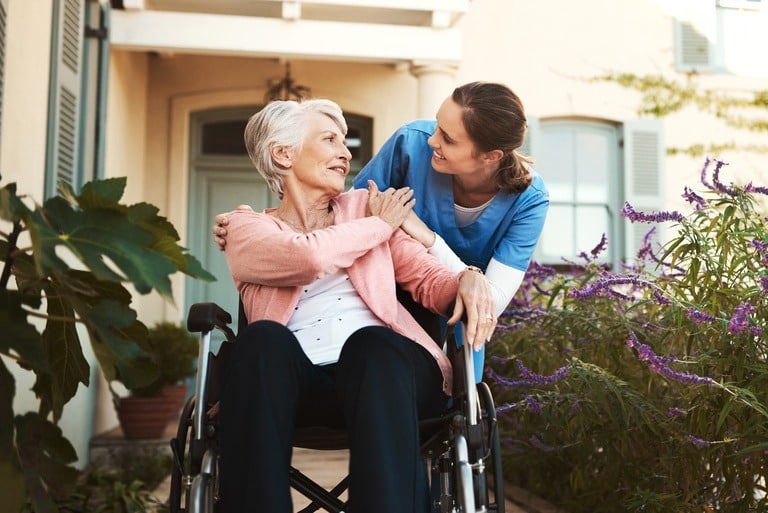 practical nurse talking to older woman in wheelchair